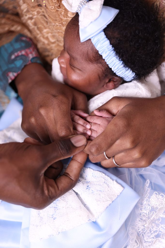Touching scene of a baby grasping parents' fingers, symbolizing family love.